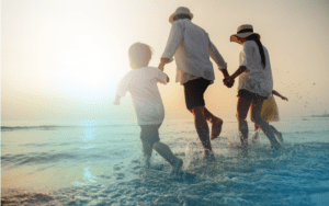 Family of 4 on splashing in the waves on a beach